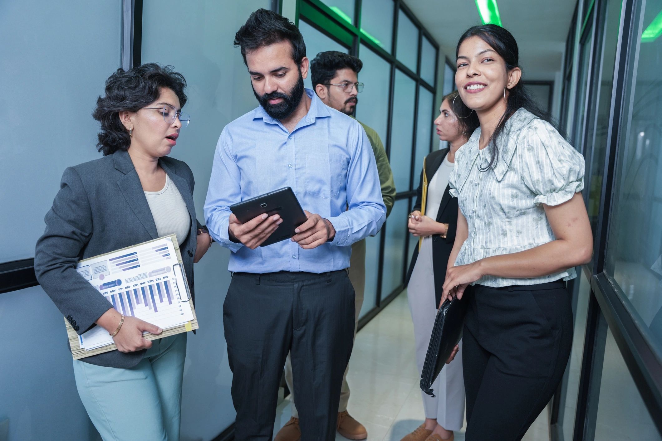 Business team discussing documents in an office hallway
